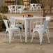 A Lancaster Table & Seating white table with four white chairs on a patio.