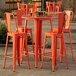 A Lancaster Table & Seating round amber orange outdoor table with 4 cafe barstools.