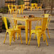 A Lancaster Table & Seating citrine yellow table and chairs on an outdoor patio.