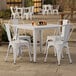 A Lancaster Table & Seating pearl white table with four white chairs on an outdoor patio.