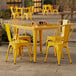 A Lancaster Table & Seating citrine yellow table with 4 chairs outside on a patio.