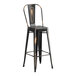 A Lancaster Table & Seating distressed copper bar height table with two black metal cafe barstools with wooden seats.