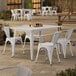 A Lancaster Table & Seating white table with 4 arm chairs on a patio.