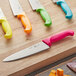 A Choice 8" chef knife with a neon green handle on a wooden surface.