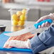 A person cutting a piece of meat with a Choice cimeter knife with a blue handle.