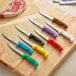 A group of Choice utility knives with colorful handles on a cutting board.