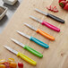 A Choice paring knife with a neon blue handle next to strawberries.