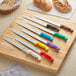 A group of Choice bread knives with black handles on a wooden surface.