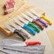 A group of Choice chef knives with different colored handles on a cutting board.