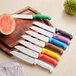 A group of Choice Santoku Knives with different colored handles on a cutting board.