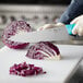 A person using a Choice chef knife to cut cabbage.