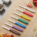 Choice paring knives with yellow handles on a cutting board.