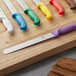 A Choice serrated bread knife with a brown handle on a cutting board.