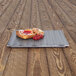 A black Elite Global Solutions melamine platter with a pastry and a raspberry on it.