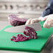 A person using a Choice 10" chef knife to cut cabbage on a cutting board.