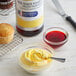 A bowl of yellow and white cupcakes with McCormick Egg Yellow Food Color on the side.