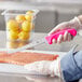 A person holding a Choice neon pink fillet knife cutting a piece of salmon.
