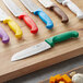 A group of Choice Santoku knives with green handles on a cutting board.