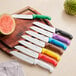 A Choice Santoku knife with a green handle on a cutting board with a watermelon.