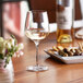 A Nude Refine white wine glass filled with white wine on a table.