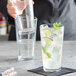 A person pouring a glass of water into a Pasabahce Grande stackable beverage glass.