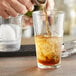 a glass of ice tea with brown liquid
