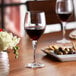A close-up of a Nude Primeur goblet filled with red wine on a table.