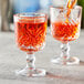 A Pasabahce Timeless Vintage stemmed shot glass filled with red liquid on a table in a cocktail bar.