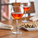Two Nude Reserva wine glasses filled with red wine on a table.