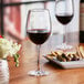 A Nude Reserva wine glass filled with red wine on a table.