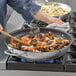 A woman cooking seafood rice and mussels in a Vigor stainless steel non-stick fry pan with a wooden spoon.