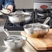 A woman using a Vigor stainless steel saucier pan on a stove.