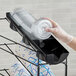 A hand in a glove putting a plastic cup into a San Jamar Wireworks cup and lid organizer tray.