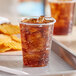 A close-up of an EcoChoice PLA plastic cup with a brown drink and a tray of chips.