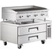 A large stainless steel countertop with a Cooking Performance Group lava briquette charbroiler and 2 drawer refrigerated chef base.