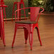 A Lancaster Table & Seating red metal arm chair with a wooden seat at a table in a restaurant.