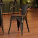 A Lancaster Table & Seating black metal chair with a walnut wood seat.