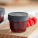 Two Ball regular mouth glass canning jars filled with raspberry jam on a table.