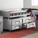 A woman in a commercial kitchen using a large Cooking Performance Group countertop griddle.