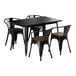 A black Lancaster Table & Seating dining table with black metal chairs with walnut wood seats.