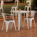 A Lancaster Table & Seating white table and 2 chairs with walnut seats in a restaurant dining area.