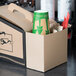 A cardboard box with Sabert coffee take out containers, a green and white cup, and straws on a table.