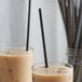 Two glasses with brown liquid and Choice black straws.