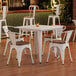 A Lancaster Table & Seating white table and chairs with walnut seats in a restaurant dining area.
