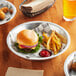 A Baker's Mark aluminum pie pan filled with a cheeseburger and a bowl of ketchup on a table.