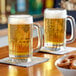 Two Libbey beer mugs filled with beer on a table.