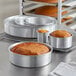 A group of round metal cake pans with food in them.