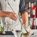 A man using an Arcoroc matte black teardrop bar spoon in a cocktail.