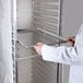 A person in a white coat opening a Curtron translucent white bun pan rack cover to put a tray on a shelf.