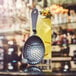 A Arcoroc stainless steel julep strainer on a glass of liquid.